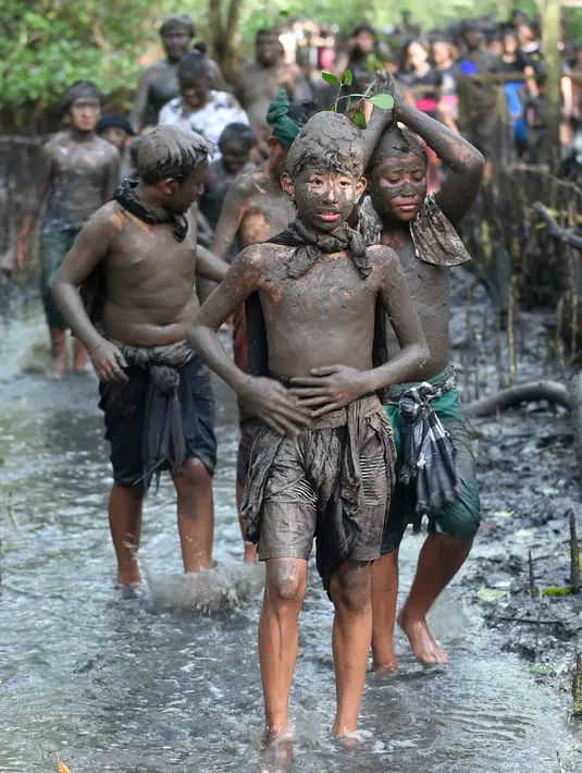 Warga berjalan menyusuri hutan mangrove saat mengikuti tradisi mandi lumpur atau mebuug-buugan di Desa Kedonganan, Denpasar, Bali, Jumat (8/3). Mebuug-buugan diikuti oleh para orang tua, remaja, hingga anak-anak. (Sonny Tumbelaka/AFP)