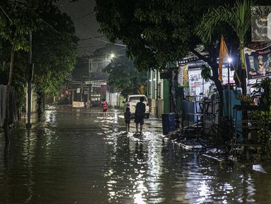 Warga melintas di genangan banjir di kawasan Mampang Prapatan, Jakarta, Sabtu (13/11/2021). Intensitas hujan yang tinggi sejak sore di Jakarta membuat kawasan permukiman di Mampang Prapatan tergenang banjir dengan tinggi sebetis orang dewasa. (Liputan6.com/Faizal Fanani)
