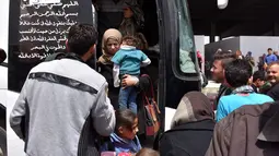 Seorang ibu menggendong anaknya saat tiba di sebuah tempat penampungan sementara di Jibrin di pinggiran timur Aleppo, Jumat (21/4). Pengungsi adalah warga dari kota Fuaa dan Kafraya. (AFP PHOTO / George OURFALIAN)