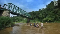 Pengendara roda dua memanfaatkan jasa perahu rakit untuk menyeberangi Sungai Cisadane di Rumpin, Bogor, Selasa (13/3). Akibat rusaknya jembatan akses  utama Rumpin-Ciseeng, warga menaiki perahu rakit dengan tarif Rp10.000. (Merdeka.com/Arie Basuki)