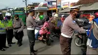 Petugas Satlantas Polres Tasikmalaya, Jawa Barat tengah membagikan selembaran termasuk masker kepada pengguna jalan, sebagai upaya sosialisasi larangan mudik 2021 yang disampaikan pemerintah pusat beberapa waktu lalu. (Liputan6.com/Jayadi Supriadin)