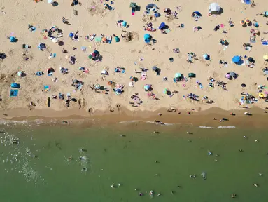 Foto udara menunjukkan orang-orang bermain dan bersantai di bawah sinar matahari di Pantai Bournemouth, Selatan Inggris pada Selasa 26 Mei 2026, saat kondisi gelombang panas menyebar ke sebagian wilayah tenggara Inggris dan London. (JUSTIN TALLIS/AFP)