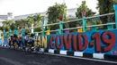 Pengendara sepeda beristirahat di dekat dinding bermural yang mengajak orang untuk memakai masker di tengah pandemi Covid-19 di Surabaya, Jawa Timur, Minggu (25/10/2020). Dinding itu dipenuhi dengan pesan untuk mematuhi protokol kesehatan di tengah pandemi Covid-19. (Juni Kriswanto/AFP)