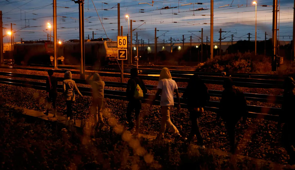 Para imigran berjalan disamping rel Channel Tunnel yang menghubungkan Prancis-Inggris di Frethun, Calais, Perancis (3/8/2015). Pada malam hari imigran masuk keterowongan rel bawah laut yang menghubungkan Perancis dan Inggris. (REUTERS/Pascal Rossignol)