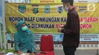 Petugas memeriksa surat hasil tes cepat COVID-19 kepada warga yang hendak memasuki kawasan yang menerapkan lockdown skala mikro akibat warga di kawasan tersebut terpapar COVID-19 di RW 03, Kelurahan Gandasari, Kecamatan Jatiuwung, Kota Tangerang, Rabu (9/6/2021). (Liputan6.com/Angga Yuniar)