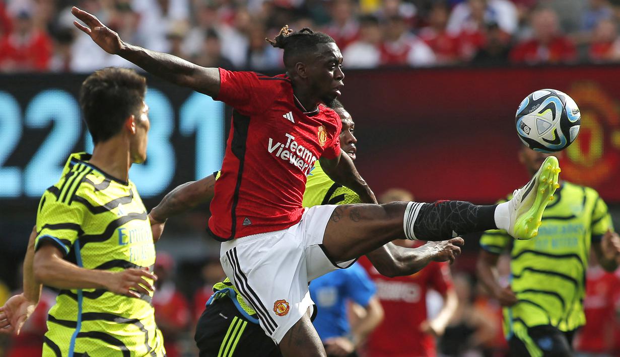 Bek Manchester United, Aaaron Wan-Bissaka mengontrol bola di antara dua pemain Arsenal, Takehiro Tomiyasu dan Gabriel Magalhaes pada laga pramusim 2023/2024 di MetLife Stadium, New Jersey, USA, Minggu (23/7/2023) pagi WIB. (AFP/Leonardo Munoz)