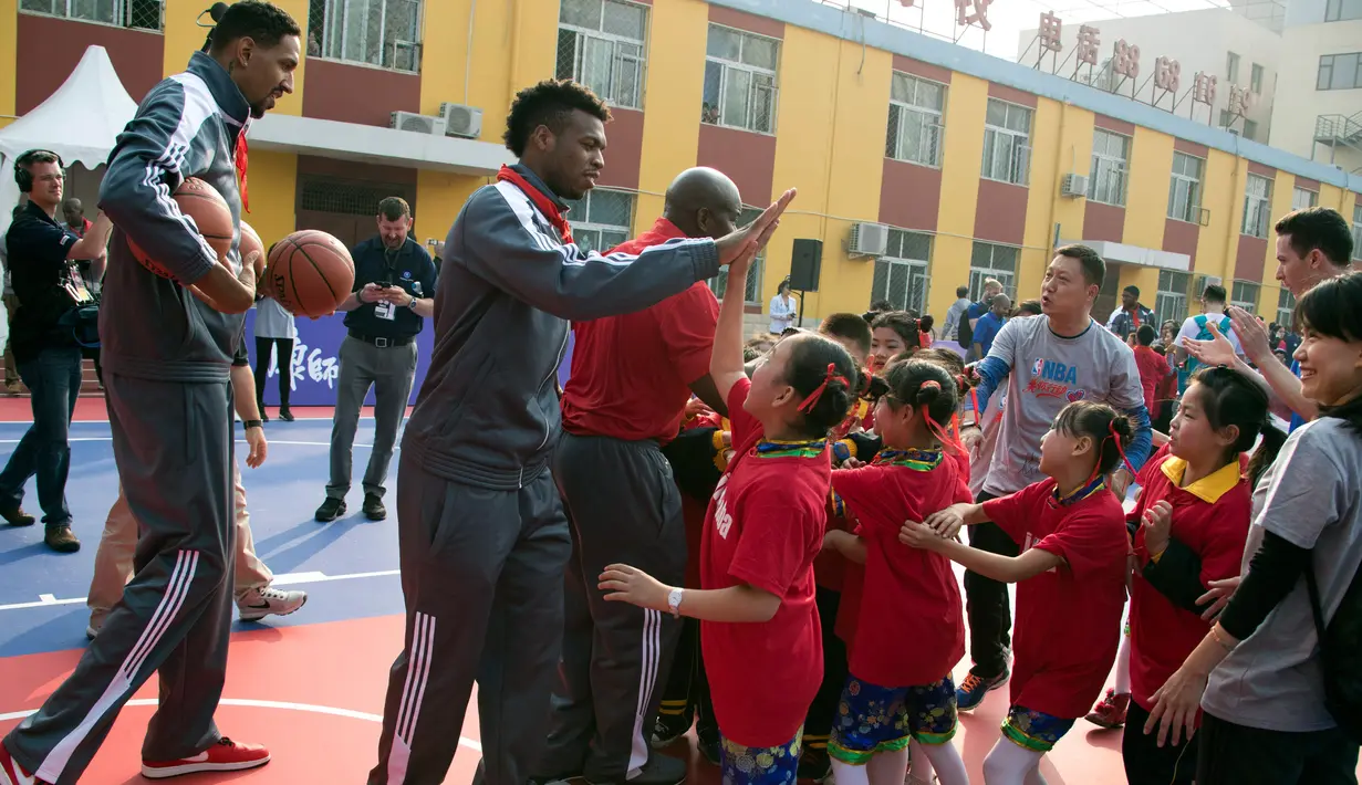 Pemain New Orleans Pelicans, Buddy Hield dan Alexis Ajinca menyapa murid di Sekolah Migran Huangzhuang, Beijing, Tiongkok (11/10). Mereka datang ke Tiongkok dalam rangka NBA Global Games. (AP Photo/Ng Han Guan)