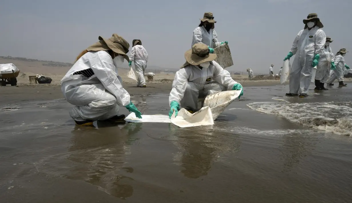 Petugas kebersihan bekerja untuk mengeluarkan minyak dari Pantai Cavero di Callao, Peru, 26 Januari 2022. Pembersihan Pantai Cavero dari tumpahan minyak kapal tanker Mare Doricum yang dihantam gelombang akibat letusan gunung berapi Tonga masih terus dilakukan. (Cris BOURONCLE/AFP)