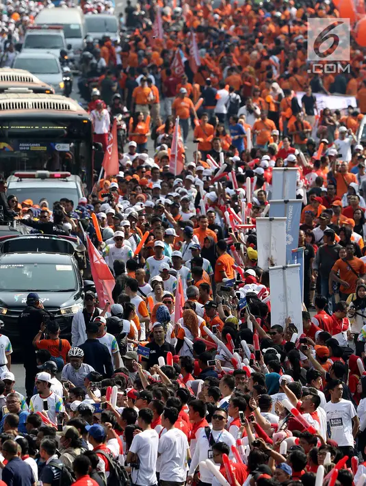 Warga menyambut kedatangan obor saat prosesi Torch Relay Asian Games 2018 di Jalan Jendral Sudirman, Jakarta, Sabtu (18/8). Hari terakhir kirab obor Asian Games ini api abadi dibawa dari Tugu Monas hingga Gelora Bung Karno. (Liputan6.com/ Fery Pradolo)