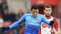 Striker Arsenal, Alexis Sanchez, berebut bola dengan bek Southampton, Jack Stephens, pada laga Premier League di Stadion St Mary's, Minggu (10/12/2017). Arsenal bermain imbang 1-1 dengan Southampton. (AP/Adam Davy)