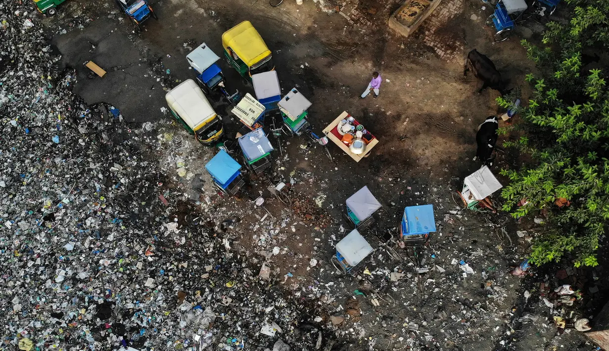Pandangan udara menunjukkan seorang pria berjalan di samping becak yang diparkir di dekat saluran pembuangan air limbah yang dipenuhi sampah di lingkungan berpenghasilan rendah di New Delhi, India (4/10/2019). (AFP Photo/Noemi Cassanelli)