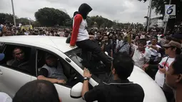 Demonstran berusaha mencegat driver online yang masih beroperasi saat unjuk rasa di depan Istana Negara, Jakarta, Rabu (14/2). Aksi pemberhentian mobil taksi online itu membuat situasi tegang antar pengemudi dan demonstran. (Liputan6.com/Arya Manggala)