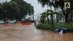 Petugas mengecek genangan air di Jalan Medan Merdeka Barat, Jakarta, Kamis (24/1/2020). Hujan deras yang mengguyur Jakarta sejak pagi tadi mengakibatkan genangan air di Jalan Medan Merdeka Barat. (Liputan6.com/Faizal Fanani)