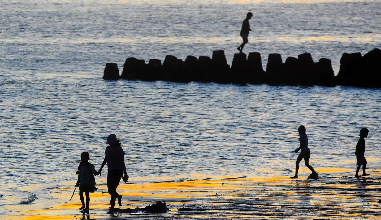 Hamparan pasir putih kecoklatan yang halus menyambut setiap wisatawan yang datang. Pasirnya nyaman untuk berjalan tanpa alas kaki, sementara deburan ombak memberikan nuansa rileks khas pantai Bali. Area pantai yang cukup luas juga memungkinkan pengunjung duduk santai di tepi pantai, baik di atas pasir maupun di area penahan abrasi yang tersedia. Tampak dalam foto, aktivitas wisatawan menikmati waktu senja di Pantai Kelan, Badung, Bali. (merdeka.com/Arie Basuki)