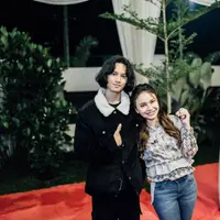 Di foto ini, Rizky terlihat mengenakan double-breasted jacket berwarna hitam dengan detail bulu putih di bagian kerahnya, dipadunya dengna celana panjang hitam. Rambutnya yang panjang dibiarkan tergerai begitu saja. Foto: Instagram.