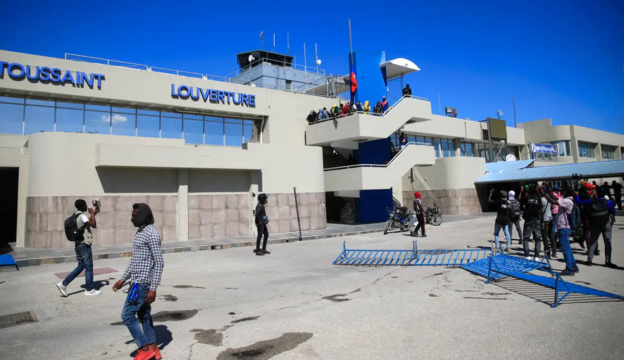 Para pengunjuk rasa masuk ke dalam halaman bandara internasional selama demonstrasi untuk mengecam buruknya tata kelola polisi di Port-au-Prince, Haiti, 26 Januari 2023. Radio Tele Metronome Haiti melaporkan bahwa para pengunjuk rasa mencoba untuk mengakses bandara dengan memecahkan jendela. (AP Photo/Odelyn Joseph)
