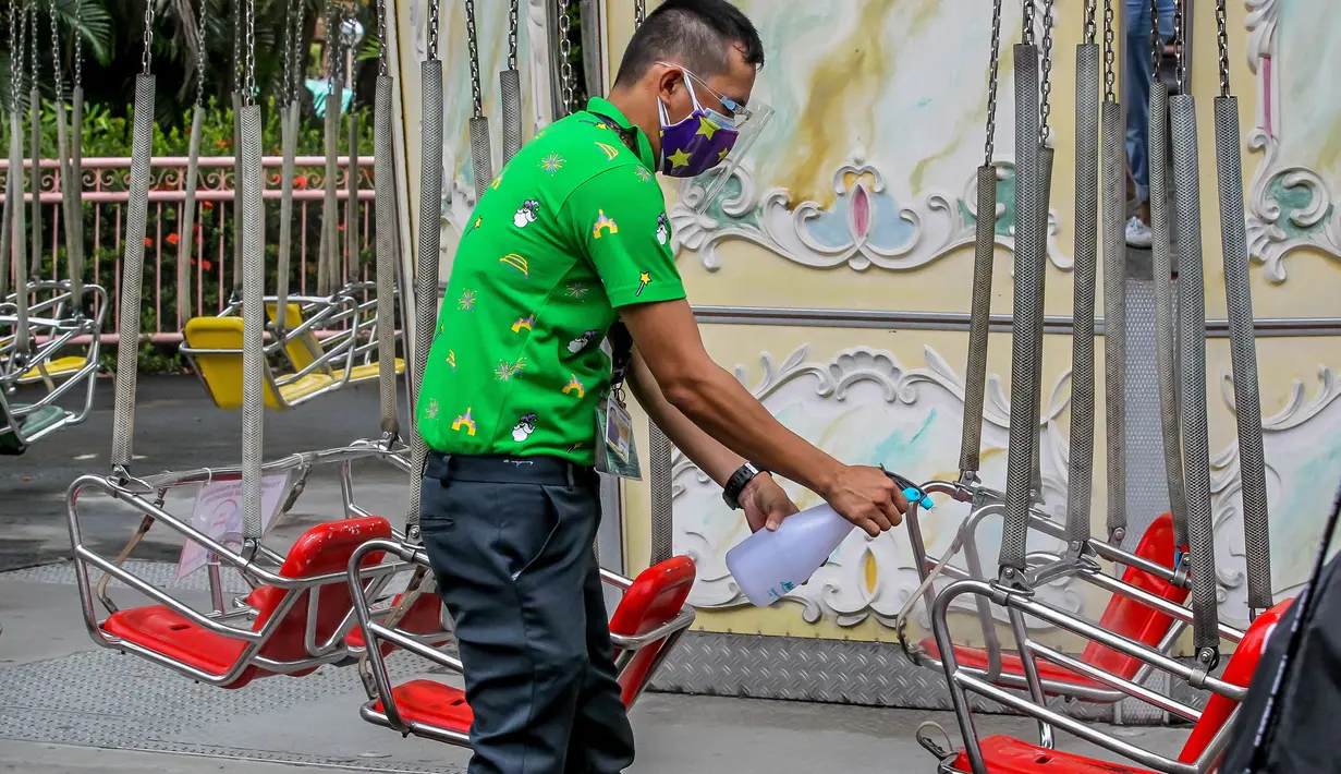 Seorang staf yang mengenakan masker mendisinfeksi wahana di taman hiburan Enchanted Kingdom di Provinsi Laguna, Filipina (18/10/2020). Taman hiburan tersebut kembali dibuka untuk pengunjung. (Xinhua/Rouelle Umali)