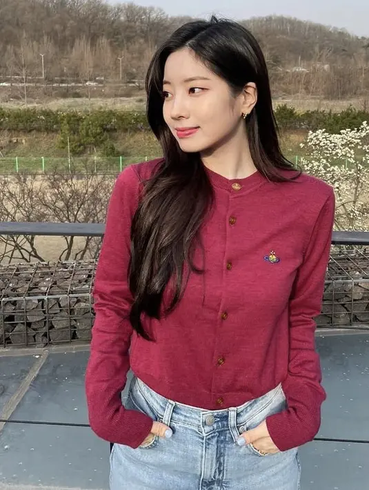 Dahyun Twice mengenakan cardigan merah yang dimasukan ke dalam celana denimnya. Gaya ini membuat Dahyun terlihat santai namun tetap rapi. Dok. Instagram @twicetagram