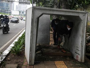 Pejalan kaki melintas di antara beton saluaran air yang berada di jalur pedestrian kawasan Gatot Subroto, Jakarta, Selasa (21/12/2021). Selain mengganggu kenyamanan, keberadaan beton saluran air tersebut juga dapat membahayakan pejalan kaki yang melintas. (Liputan6.com/Faizal Fanani)