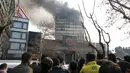 Warga menyaksikan kebakaran yang melanda gedung pencakar langit tertua Iran, gedung Plasco berlantai 15 di pusat kota Teheran, Kamis (19/1). Beberapa bagian bangunan runtuh di tengah upaya pemadam kebakaran menjinakkan api. (AP Photo/Vahid Salemi)