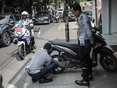 Petugas Dishub DKI Jakarta merazia  kendaraan roda dua dengan mencopot pentil yang terparkir di trotoar di kawasan Cipete Raya, Jakarta, Selasa (13/8/2019). Razia tersebut dilakukan Dishub untuk mengembalikan fungsi trotoar