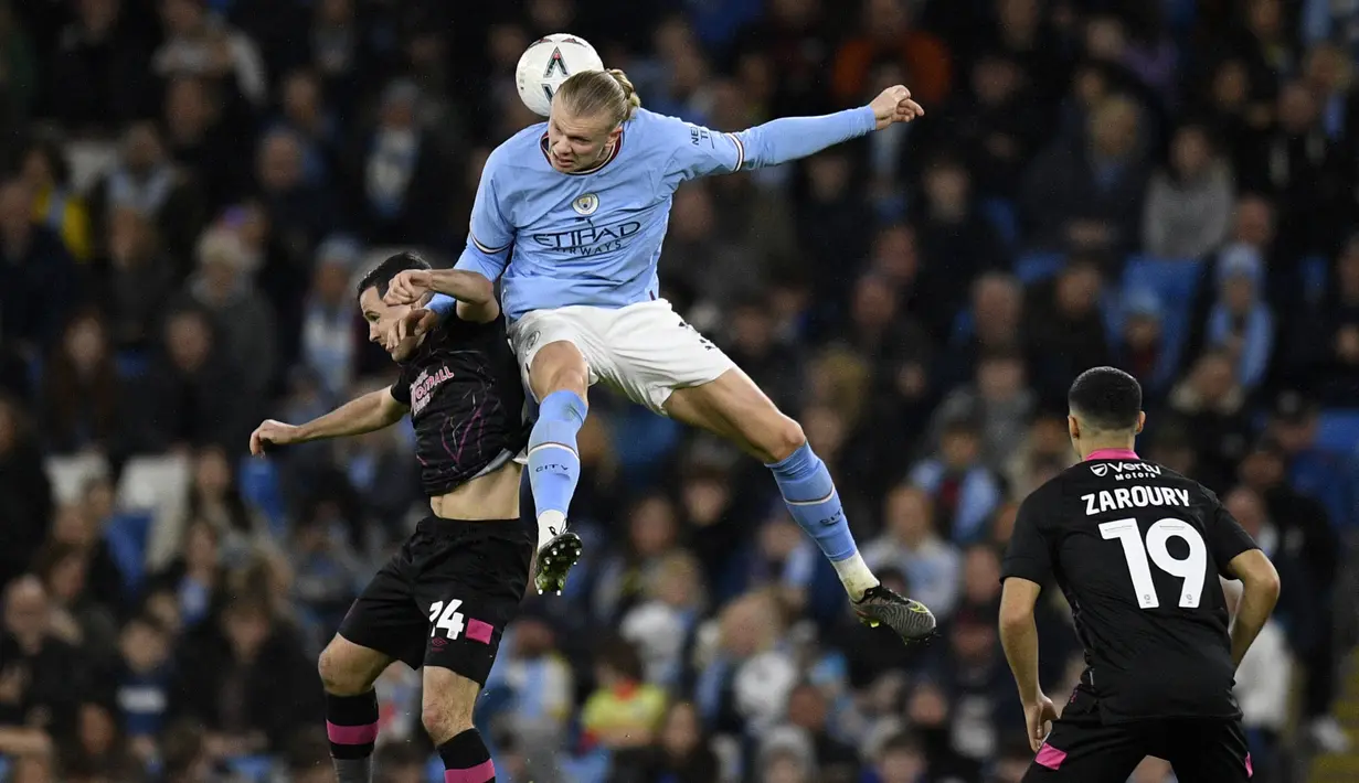 Pemain Manchester City, Erling Haaland (tengah) berebut bola dengan pemain Burnley, Josh Cullen pada laga perempat final FA Cup 2022/2023 yang berlangsung di Etihad Stadium, Manchester, Minggu (19/03/2023) WIB. Haaland sukses mencetak hattrick untuk kemenangan 6-0 The Cityzens. (AFP/Oli Scarff)