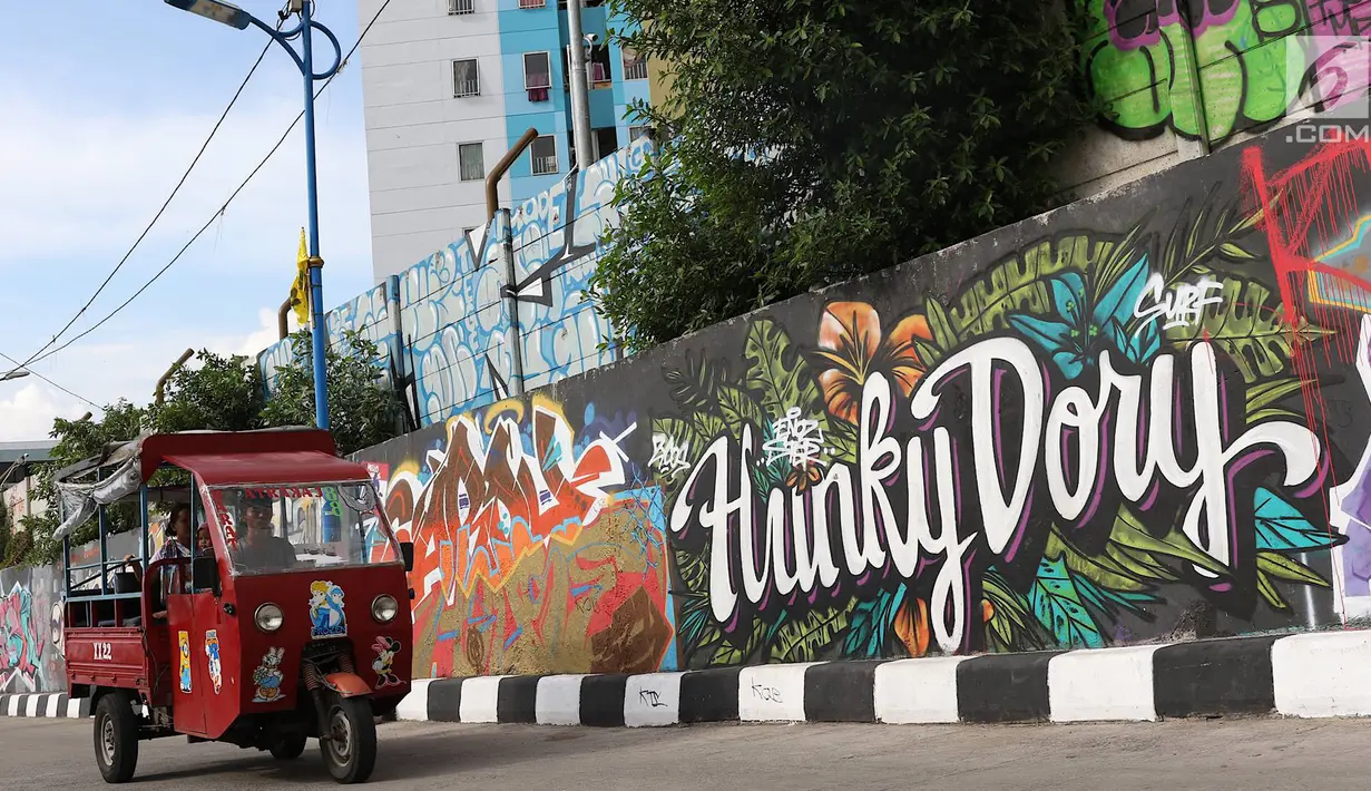 Pengendara melintasi jalur inspeksi Sungai Ciliwung di Jakarta, Kamis (27/12). Mural yang dibuat oleh beberapa komunitas tersebut menjadikan jalur inspeksi Sungai Ciliwung tampak lebih berwarna dan asri. (Liputan6.com/Immanuel Antonius)