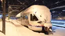 Sebuah kereta komuter tertutup salju di Stasiun Berchtesgaden, Jerman, Kamis (10/1). Transportasi kereta api berhenti karena hujan salju lebat. (Tobias Hase/dpa/AFP)