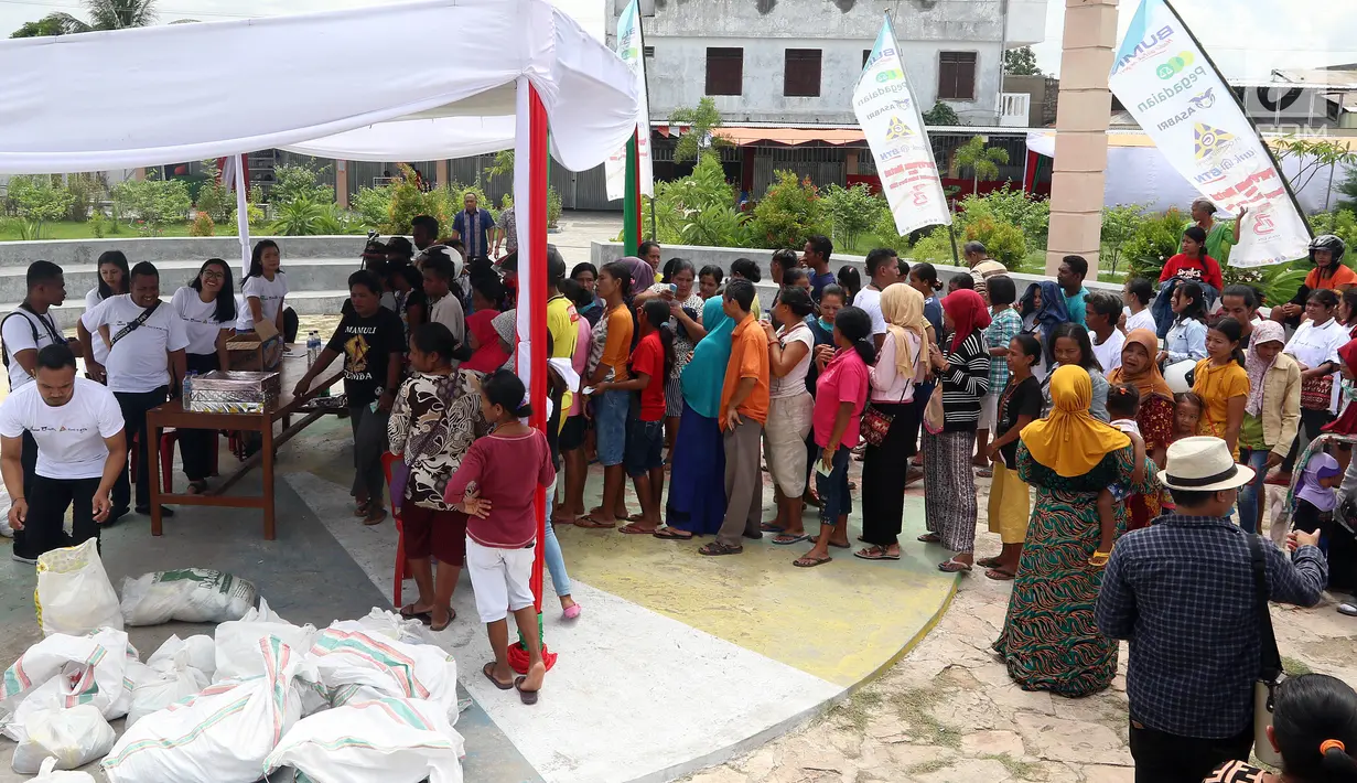 Warga mengantre sembako saat Sinergi empat BUMN memberikan bantuan di Kota Waingapu, Sumba Timur, Sabtu (15/12). Sinergi empat BUMN ini adalah PT ASABRI (Persero), PT Pegadaian, PT Garam dan Bank BTN. (Liputan6.com/JohanTallo)