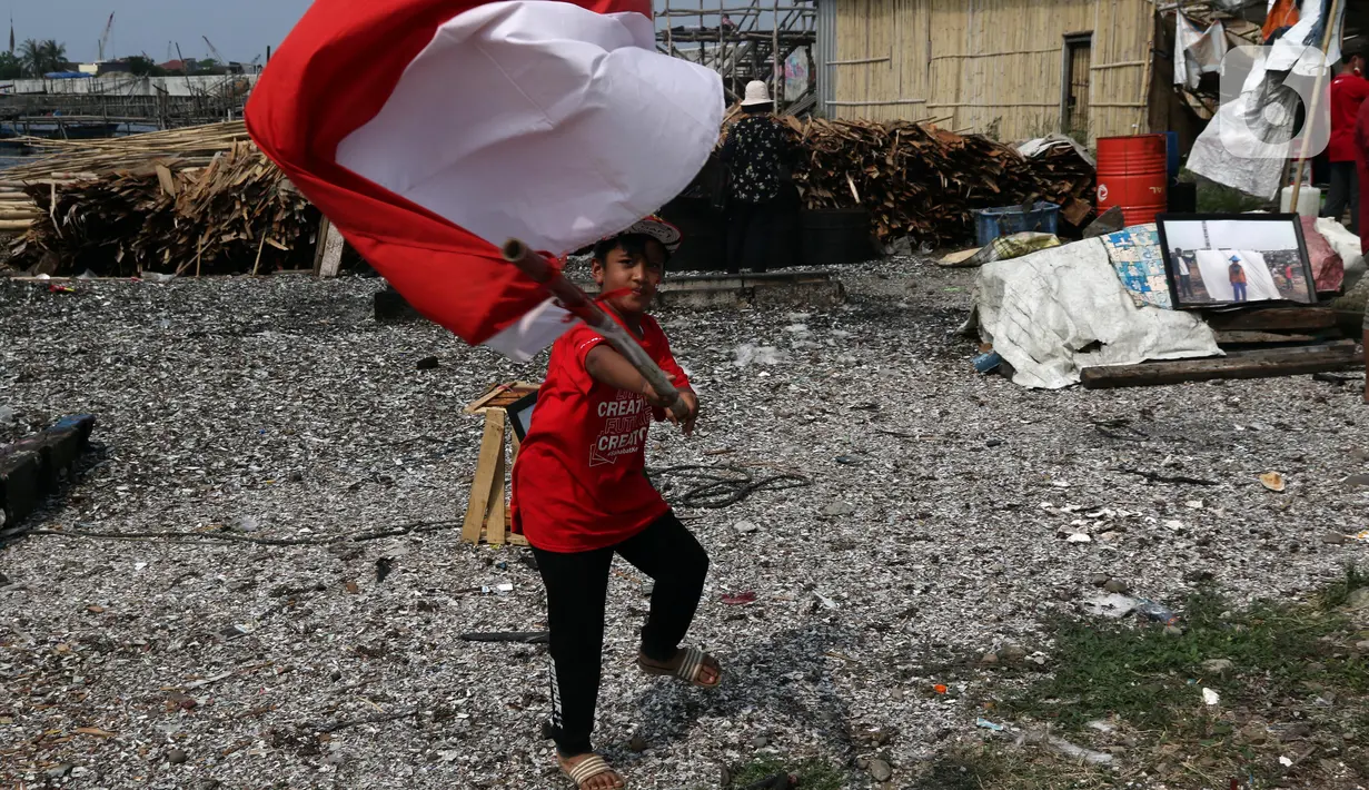 Seorang anak mengibar-ngibarkan bendera Merah Putih usai pelaksanaan Upacara Peringatan HUT RI ke-77 di Kawasan Kalibaru Barat, Cilincing, Jakarta, Rabu (17/8/2022). Memperingati Hari Kemerdekaan Indonesia ke-77, anak-anak yang tergabung dalam Kelas Jurnalis Cilik bersama para relawan melaksanakan upacara bendera dan beragam lomba. (Liputan6.com/Helmi Fithriansyah)