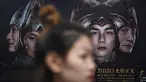 Seorang wanita berjalan melewati poster film Asura di stasiun kereta bawah tanah di Beijing, Selasa (17/7). Tim produser secara tiba-tiba menarik kembali Asura, film termahal di China yang baru tayang sepekan di bioskop. (AFP/GREG BAKER)