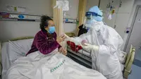 Petugas medis membagikan buah-buahan kepada pasien yang terinfeksi virus corona COVID-19 di rumah sakit Palang Merah di Wuhan, 16 Februari 2020. Covid-19 telah mewabah hingga ke lebih dari 60 negara dimana dari kasus-kasus infeksi, ada lebih dari 3.000 kematian yang terjadi.  (STR/AFP)
