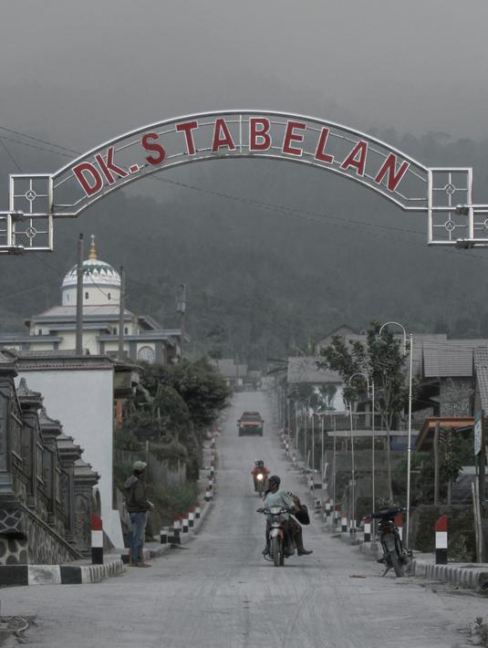 Pengendara berkendara di jalan yang tertutup abu setelah letusan Gunung Merapi di desa Stabelan, Magelang pada 11 Maret 2023.Gunung Merapi yang berada di perbatasan Daerah Istimewa Yogyakarta dan Jawa Tengah kembali meletus pada Sabtu 11 Maret 2023. (AFP/Devi Rahman)