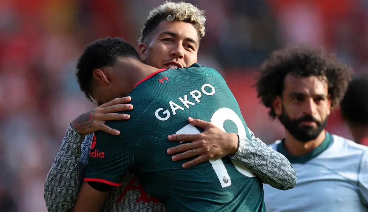 Striker Liverpool, Cody Gakpo memeluk Roberto Firmino usai laga pekan terakhir Liga Inggris 2022/2023 menghadapi Southampton di St Mary's Stadium, Southampton, Minggu (28/5/2023) malam WIB. (AFP/Adrian Dennis)
