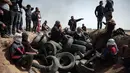 Para demonstran Palestina duduk di atas puluhan ban yang dikumpulkan untuk dibakar selama protes di perbatasan Jalur Gaza dengan Israel, (6/4). (AP Photo/Khalil Hamra)