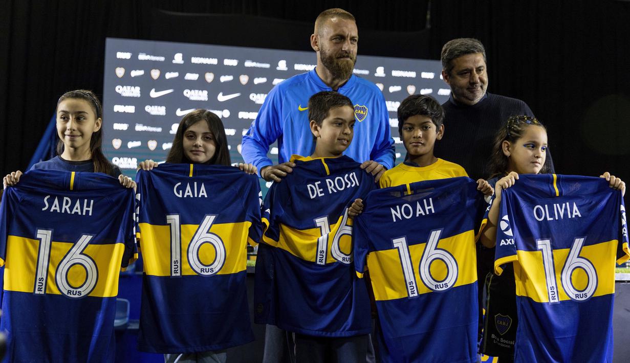 Gelandang baru Boca Juniors, Daniele De Rossi bersama Presiden Boca Juniors Daniel Angelici foto bersama dengan anak-anak selama pengenalan dirinya di Buenos Aires, Argentina (29/7/2019). De Rossi yang 36 tahun mengakhiri 18 tahun karirnya di Roma akhir musim lalu. (AP Photo/Tomas F. Cuesta)