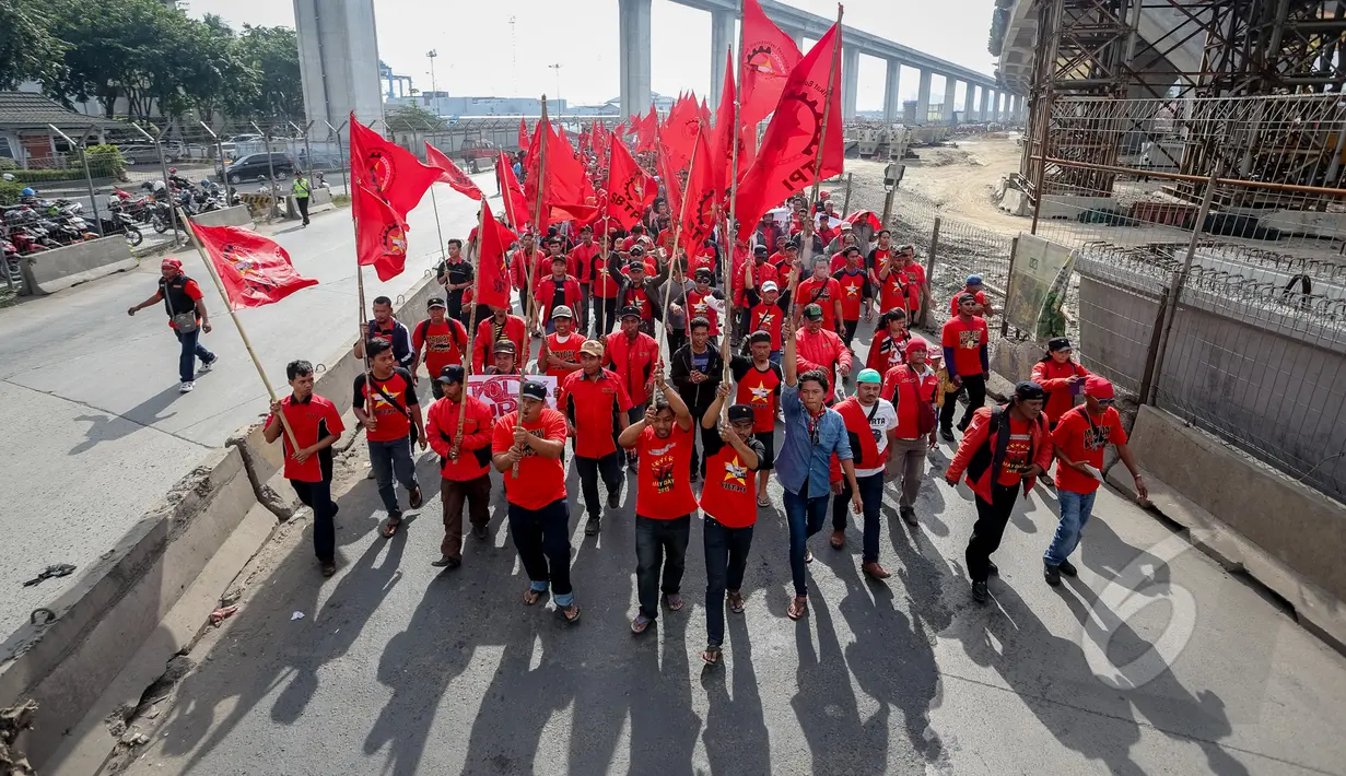 Sejumlah buruh yang tergabung dalam FSBTPI berjalan membawa bendera di kawasan Tanjung Priok , Jakarta, Jumat (1/4/2015). Tepat pada 1 Mei seluruh buruh di dunia merayakan 'Hari Raya' atau biasa disebut May Day.  (Liputan6.com/Faizal Fanani)