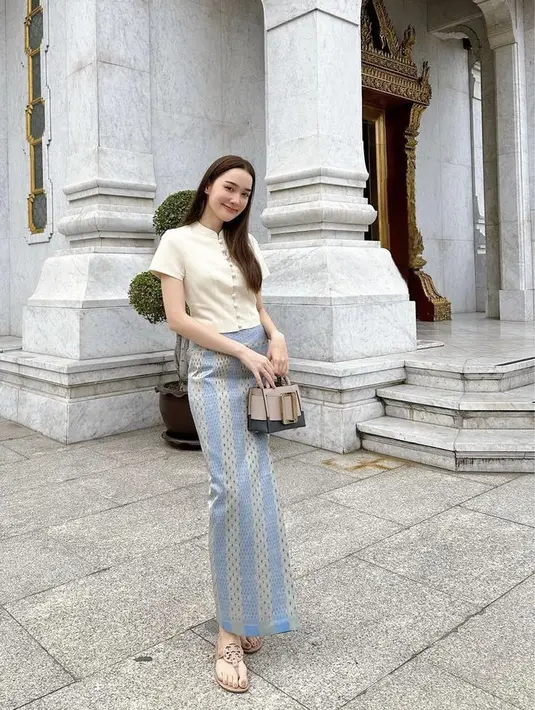 Dengan atasan putih berkancing depan, Diana memilih memadukannya dengan kain warna biru hijau sambil membawa mini bag coklat. (@dianaflipo)