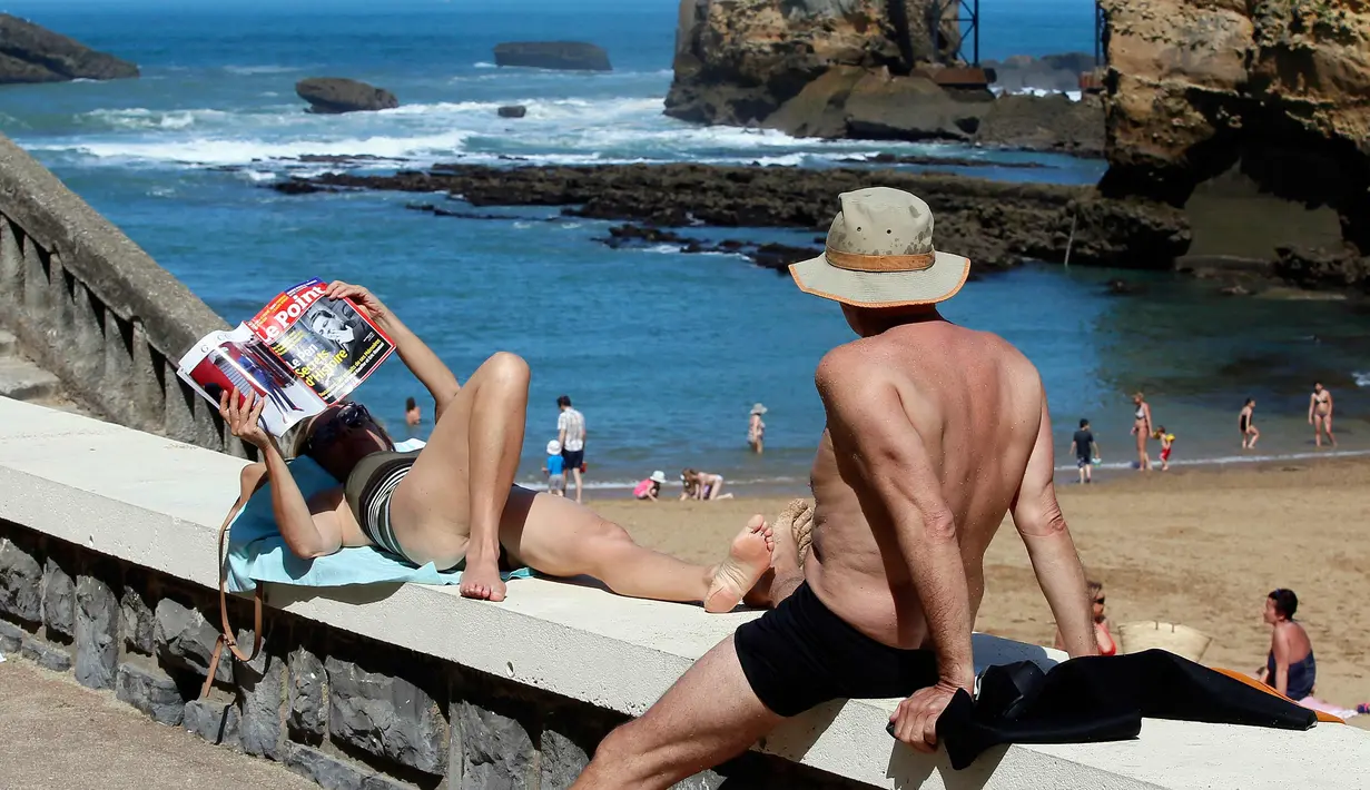Seorang wanita membaca majalah saat berjemur di pantai Port Vieux, (Old Seaport) di Biarritz, barat daya Prancis, (19/4). Suhu di Prancis barat daya telah mencapai 27 derajat Celcius (80,6 Fahrenheit). (AP Photo / Bob Edme)