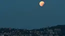 Gerhana bulan parsial terlihat kota Nice, selatan Prancis, Senin (7/8). Gerhana bulan parsial terjadi ketika bumi bergerak di antara bulan dan matahari, tapi tidak persis dalam satu garis. (YANN COATSALIOU / AFP)