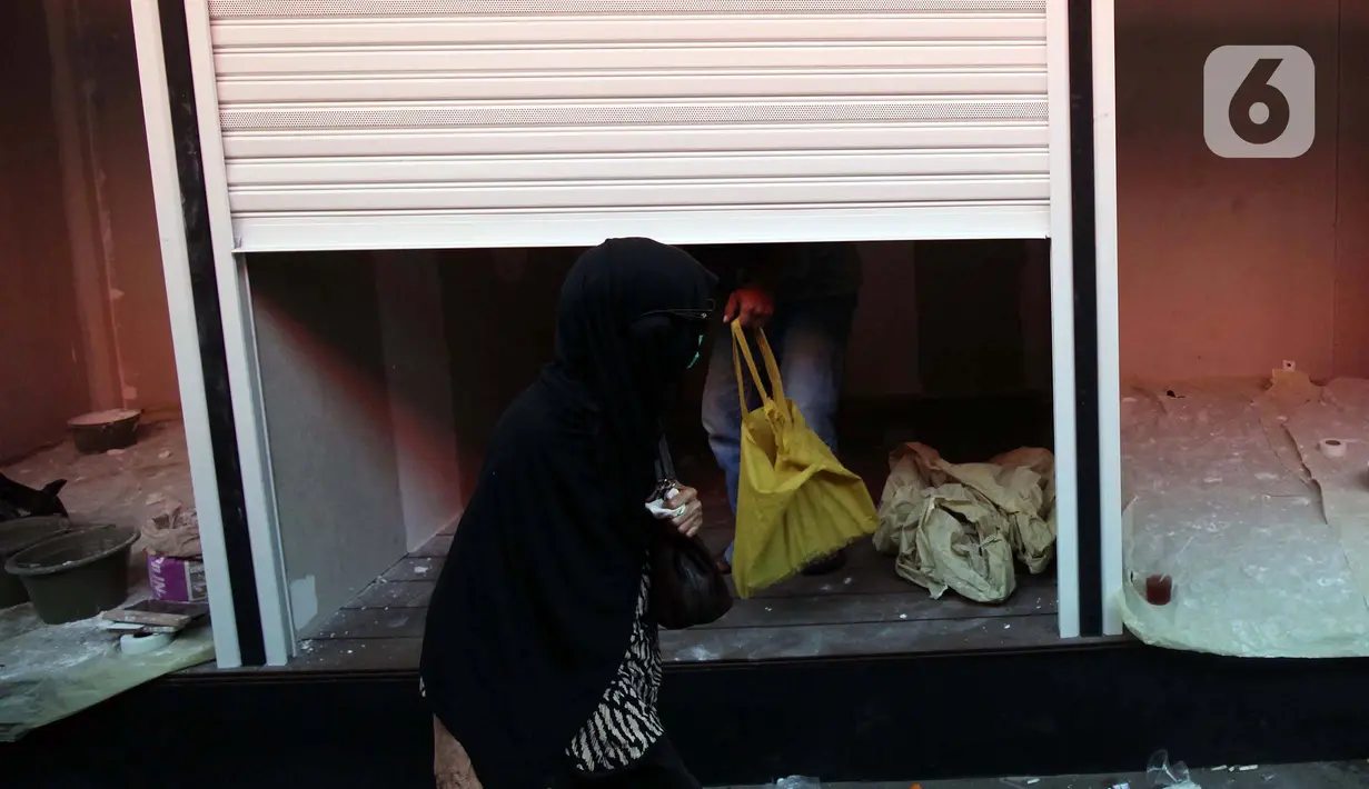Warga melintas di depan ruko yang disiapkan untuk UMKM di stasiun Gondangdia, Jakarta, Sabtu (16/10/2021). Pembuatan ruko untuk para pedaganag di kawasan sekitar stasiun tersebut bertujuan agar terlihat lebih rapi dan modern. (Liputan6.com/Johan Tallo)