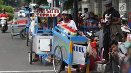 Pedagang kaki lima menjajakan makanan dan minuman di sisi jalan sekitar kawasan Patung Kuda Jakarta, Rabu (5/1/2019). Mereka mencoba peruntungan saat para buruh melakukan aksi perayaan Hari Buruh International atau May Day. (Liputan6.com/Helmi Fithriansyah)
