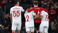 Momen saat bek Manchester United (MU) Lisandro Martinez dipapah dua pemain Sevilla Marcos Acuna (kanan) dan Gonzalo Montiel (kiri). (DARREN STAPLES / AFP)