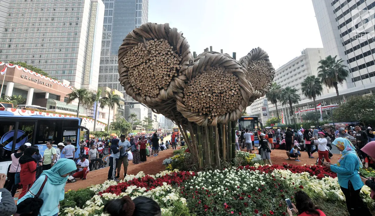Warga beraktivitas dekat karya seni bambu bernama "Getih Getah" saat kegiatan Car Free Day di Bundaran Hotel Indonesia, Jakarta Pusat, Minggu (19/8). Pilinan bambu tersebut dibuat menyambut Asian Games 2018. (Merdeka.com/Iqbal S. Nugroho)