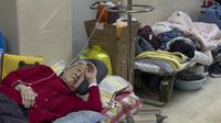 Pasien lanjut usia (lansia) beristirahat di sepanjang koridor bangsal darurat saat mereka menerima infus di Beijing, Kamis (5/1/2023). Pasien, kebanyakan dari mereka lansia, berbaring di tandu di lorong dan menerima oksigen sambil duduk di kursi roda saat kasus COVID-19 melonjak di ibu kota China, Beijing. (AP Photo/Andy Wong)