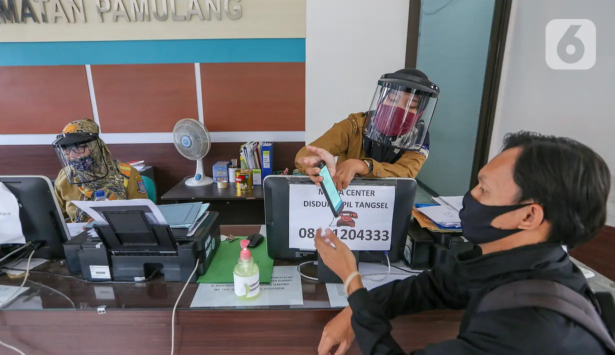 Petugas loket lengkap dengan masker dan face shield melayani warga saat proses pembuatan KTP Elektronik di Kecamatan Pamulang, Tangerang Selatan, Senin (15/6/2020). Dukcapil Tangsel membuka layanan rekaman E-KTP jelang Pilkada dengan menerapkan ketentuan New Normal. (Liputan6.com/Fery Pradolo)