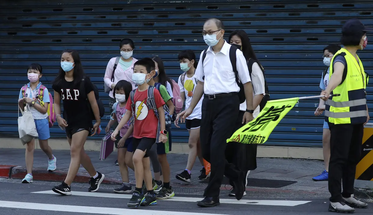 Siswa sekolah dasar mengenakan masker untuk melindungi diri dari penyebaran COVID-19 dan berjalan kaki ke sekolah di Taipei, Taiwan, Rabu (1/9/2021). Seluruh sekolah di Taiwan kembali dibuka untuk tahun ajaran baru setelah ditutup akibat pandemi COVID-19. (AP Photo/Chiang Ying-ying)
