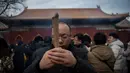 Seorang pria berdoa untuk keberuntungan pada hari kelima Tahun Baru Imlek di Yonghegong, atau Kuil Lama di Beijing (9/2). Warga China di seluruh dunia menyambut Tahun Babi pada 5 Februari.  (AFP Photo/Nicolas Asfouri)