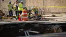 Sejumlah petugas bekerja di dekat lubang besar (sinkhole) di wilayah Brooklyn, New York, Selasa (4/8/2015). Lubang yang terbentuk di persimpangan pemukiman Sunset Park itu disebabkan erosi dan merusak pipa air serta aspal jalan. (AFP/Kena Betancur)