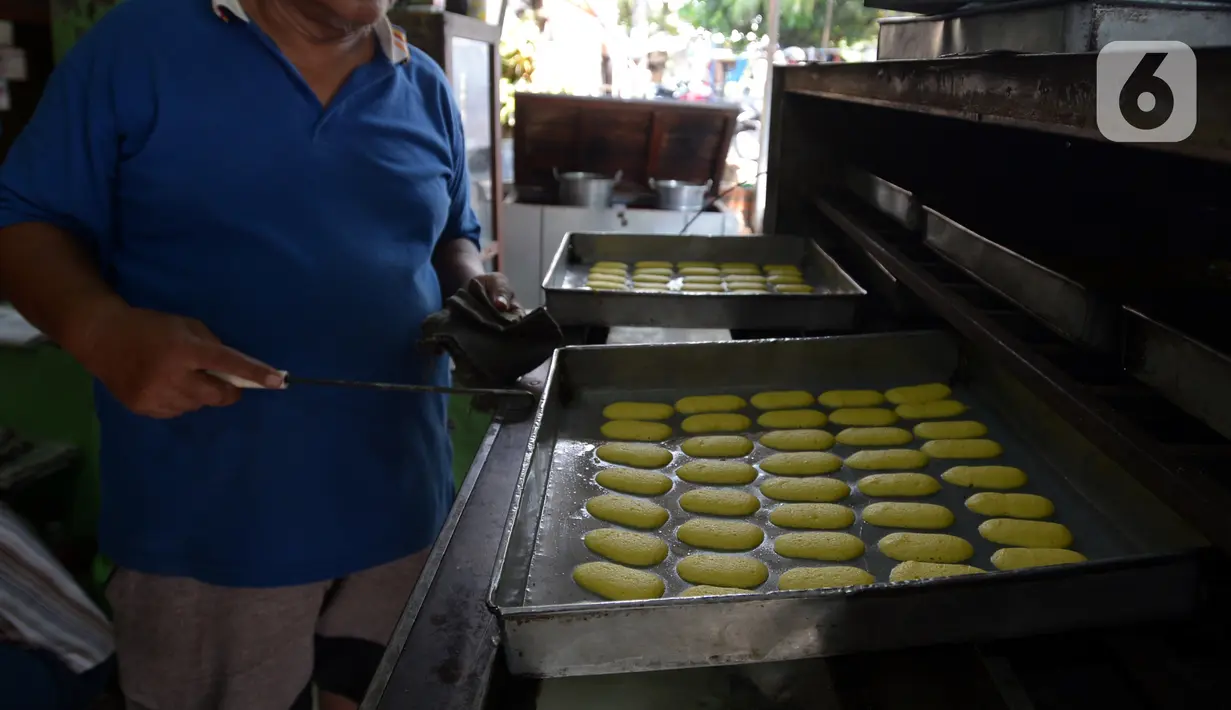 Pekerja memasukkan adonan kue kering ke dalam mesin oven di usaha pembuatan kue Pusaka Kwitang di kawasan Kwitang, Jakarta Pusat, Selasa (27/4/2021). Kue kering yang diproduksi antara lain putri salju, kastengel, nastar, kue lidah kucing, dan kue kacang. (merdeka.com/Imam Buhori)